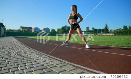 Fit woman standing with legs wide at stadium. 79106482