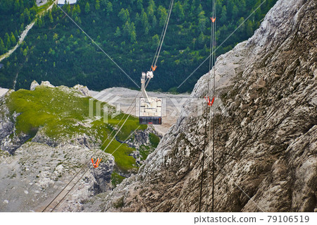 Cabin of the cable car to the Zugspitze in Bavaria hangs from the thick steel cable over the bare rocks of the Limestone Alps 79106519
