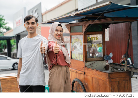 street food seller with walking stall of indonesian Chicken Satay Cooking on a Hot Charcoal Grill 79107125