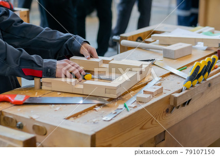 Professional man carpenter working with wooden detail - assembling process 79107150