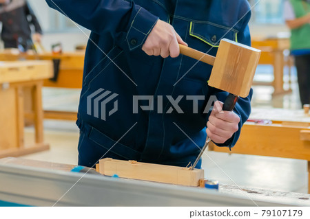Carpenter using chisel and hammer to carve wood - close up 79107179