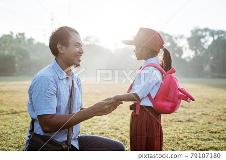 father taking her daughter to primary school in the morning father taking her daughter to primary school in the morning 79107180