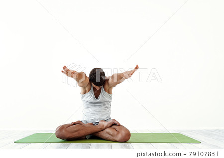 Male yoga maditates in classical pose in studio over white background 79107831