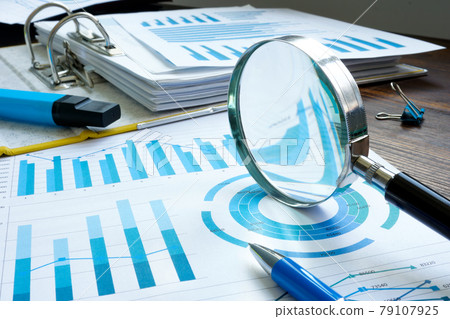 Internal audit with magnifier and financial figures and report. Internal audit with magnifier and financial figures and report. 79107925