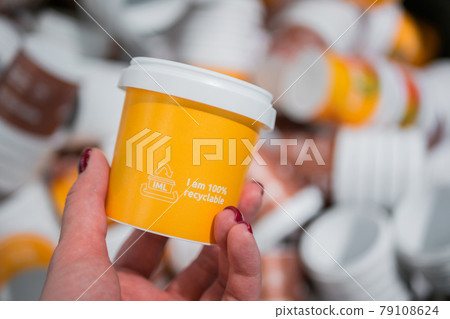 Woman hand holding yellow plastic cup - close up Woman hand holding yellow plastic cup - close up 79108624