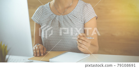 Unknown business woman working with computer while sitting at the desk in sunny office, close-up. Middle aged female lawyer at work 79108691