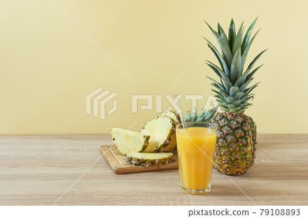 Pineapple fresh juice in glass on wooden table over yellow background. Pineapple fresh juice in glass on wooden table over yellow background. 79108893