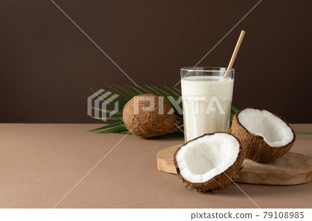 A glass of coconut vegan milk over brown background. 79108985