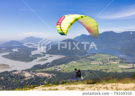 Adventurous Woman Flying on a paraglider around the Canadian Mountain Landscape Adventurous Woman Flying on a paraglider around the Canadian Mountain Landscape 79109108