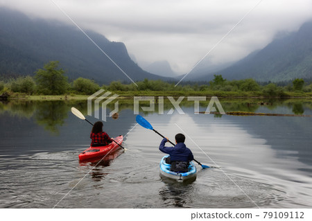 Adventure Friends Kayaking in Kayak surrounded by Canadian Mountain Landscape Adventure Friends Kayaking in Kayak surrounded by Canadian Mountain Landscape 79109112