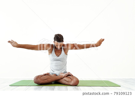 Male yoga maditates in classical pose in studio over white background Male yoga maditates in classical pose in studio over white background 79109123