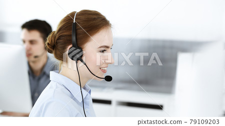 Young woman using headset and computer while talking with customers online. Group of Call center operators at work. Business concept Young woman using headset and computer while talking with customers online. Group of Call center operators at work. Business concept 79109203