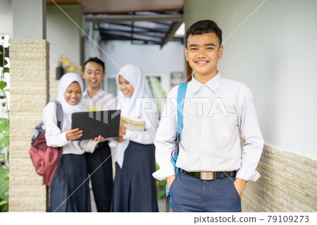 a teenager smiles at the camera in a school uniform carrying a school bag with copyspace a teenager smiles at the camera in a school uniform carrying a school bag with copyspace 79109273
