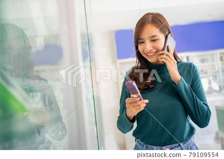 beautiful woman making a call with a smartphone while choosing cell phone accessories 79109554