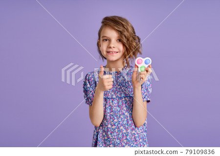 Picture of little girl with a modern popit toy. Colorful and bright pop it toy simple dimple. Trendy anti stress sensory toy fidget push pop it and simple dimple in kid's hands Picture of little girl with a modern popit toy. Colorful and bright pop it toy simple dimple. Trendy anti stress sensory toy fidget push pop it and simple dimple in kid's hands 79109836