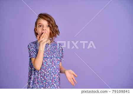 Young girl wearing flower print dress over purple isolated background shocked covering mouth with hand. Young girl wearing flower print dress over purple isolated background shocked covering mouth with hand. 79109841