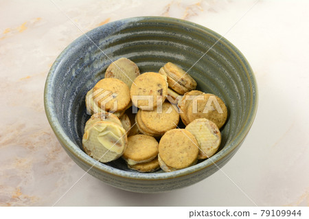Small blueberry cereal cookies covered in white chocolate on one side in snack bowl on table 79109944