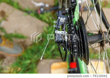 Bike mechanic man repairs bicycle in bicycle repair shop, outdoor. Hand of cyclist bicyclist examines, fixes modern cycle transmission system. Bike maintenance, sport shop concept. Bike mechanic man repairs bicycle in bicycle repair shop, outdoor. Hand of cyclist bicyclist examines, fixes modern cycle transmission system. Bike maintenance, sport shop concept. 79110442
