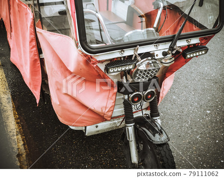 Closeup photo of a fragment of a walking motorcycle covered with a transparent red canopy 79111062