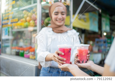 close up of two cups of fruit ice is given by the seller to the customer 79112092
