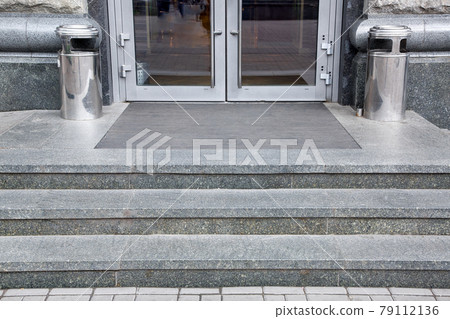 granite gray threshold steps with a foot mat at the entrance to the front door made of tempered glass architecture market style with trash can near facade, nobody. granite gray threshold steps with a foot mat at the entrance to the front door made of tempered glass architecture market style with trash can near facade, nobody. 79112136