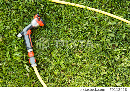 Watering garden hose nozzle on a green grass 79112438