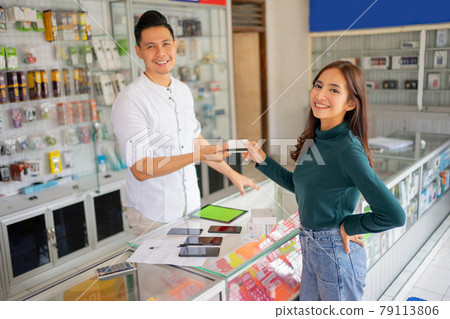 a beautiful woman smiles while giving a credit card to a man when paying a beautiful woman smiles while giving a credit card to a man when paying 79113806
