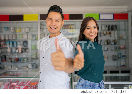 close up of a handsome young man and beautiful young woman with thumbs up on a smartphone shop close up of a handsome young man and beautiful young woman with thumbs up on a smartphone shop 79113811