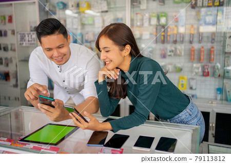 a man and a beautiful girl choose and try on a cellphone a man and a beautiful girl choose and try on a cellphone 79113812