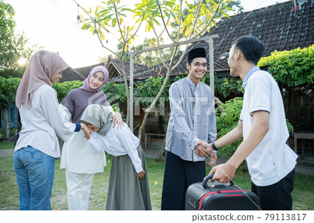 A Muslim husband, wife, and daughter shake hands with their family when they meet 79113817
