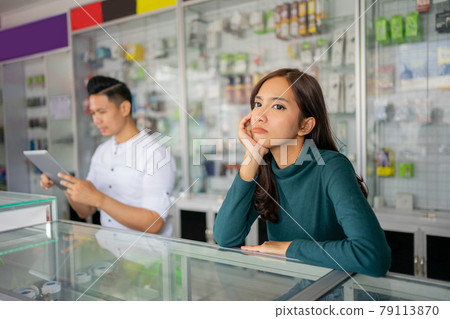 beautiful business girl pouting because there are no customers against the background in a smartphone shop beautiful business girl pouting because there are no customers against the background in a smartphone shop 79113870