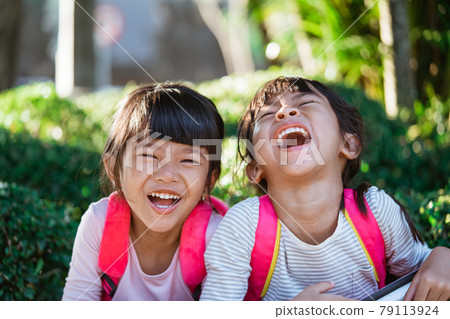 kid student laughing while sitting in the park 79113924