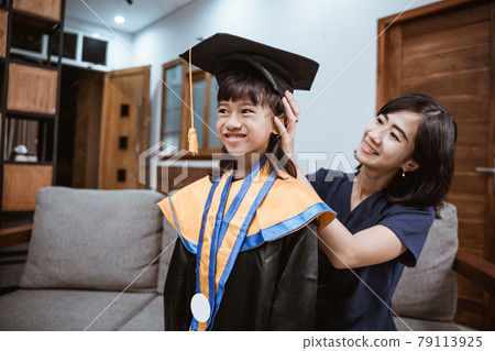 Asian mother and kid preparing on her kinder graduate day at home Asian mother and kid preparing on her kinder graduate day at home 79113925