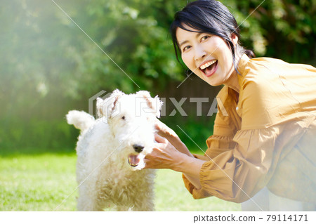 中間的女人在院子里和她的狗玩耍 79114171