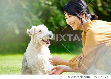 中間的女人在院子里和她的狗玩耍 中間的女人在院子里和她的狗玩耍 79114174