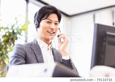 一個穿著西裝、戴著耳機、走向台式電腦的男人 79118716