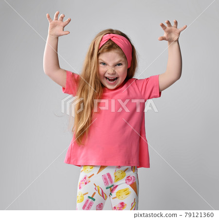 Playful, frolic redhead kid girl in pink t-shirt 79121360