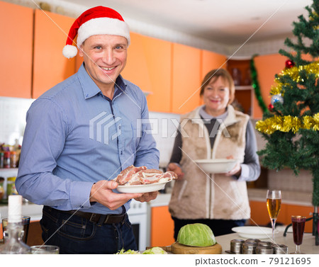 Man with plate of meat during cooking for xmas dinner Man with plate of meat during cooking for xmas dinner 79121695