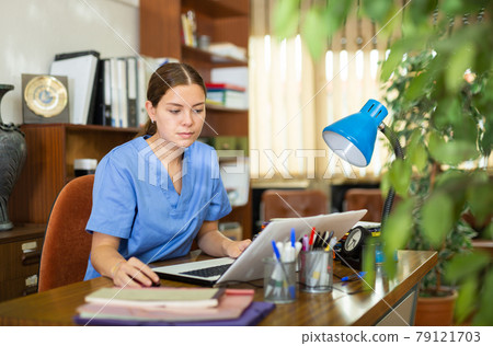 Portrait of a young doctor girl working at a computer Portrait of a young doctor girl working at a computer 79121703