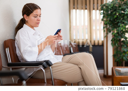 Focused young girl is sitting in the lobby, waiting for her turn Focused young girl is sitting in the lobby, waiting for her turn 79121868