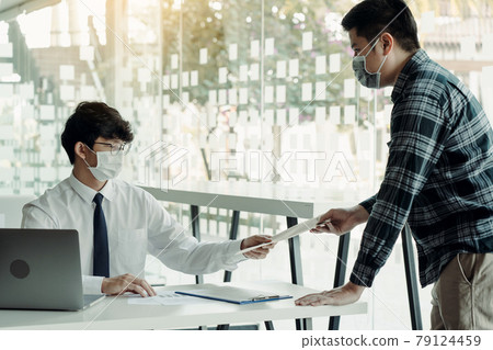 Employees submit documents at their office while wearing masks during the outbreak of the virus. Employees submit documents at their office while wearing masks during the outbreak of the virus. 79124459