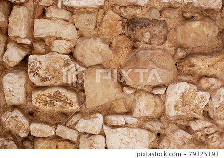 Yellow stone wall on a building as a background. The natural texture of the breed. Yellow stone wall on a building as a background. The natural texture of the breed. 79125191