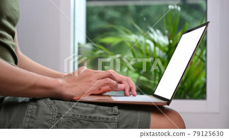 Young man sitting in living room at home and using laptop computer. Young man sitting in living room at home and using laptop computer. 79125630