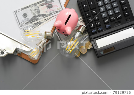 Light bulb and calculator on gray table Light bulb and calculator on gray table 79129756