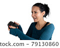 A smiling happy, concentrated young caucasian woman holding a wireless joypad excited focusing playing a digital online video game as a fun relaxing recreational leisure hobby, isolated on white 79130860