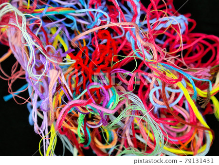 Close-up of multicolored tangled threads for needlework on black background 79131431