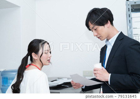 Boss and subordinates discussing documents in front of the copier Boss and subordinates discussing documents in front of the copier 79131645