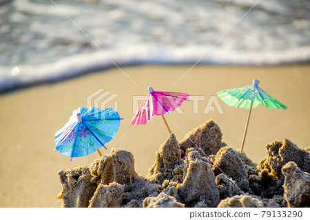 Three small beach umbrellas made of paper for cocktail stand in sand Three small beach umbrellas made of paper for cocktail stand in sand 79133290