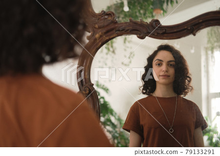 Woman looking at mirror Woman looking at mirror 79133291