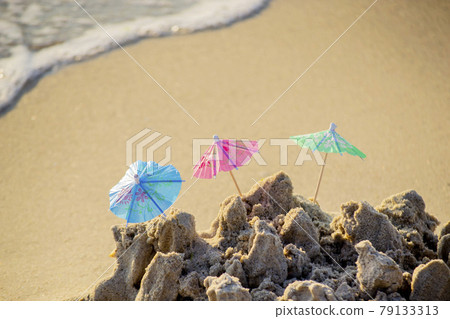 Three small beach umbrellas made of paper for cocktail stand in sand Three small beach umbrellas made of paper for cocktail stand in sand 79133313